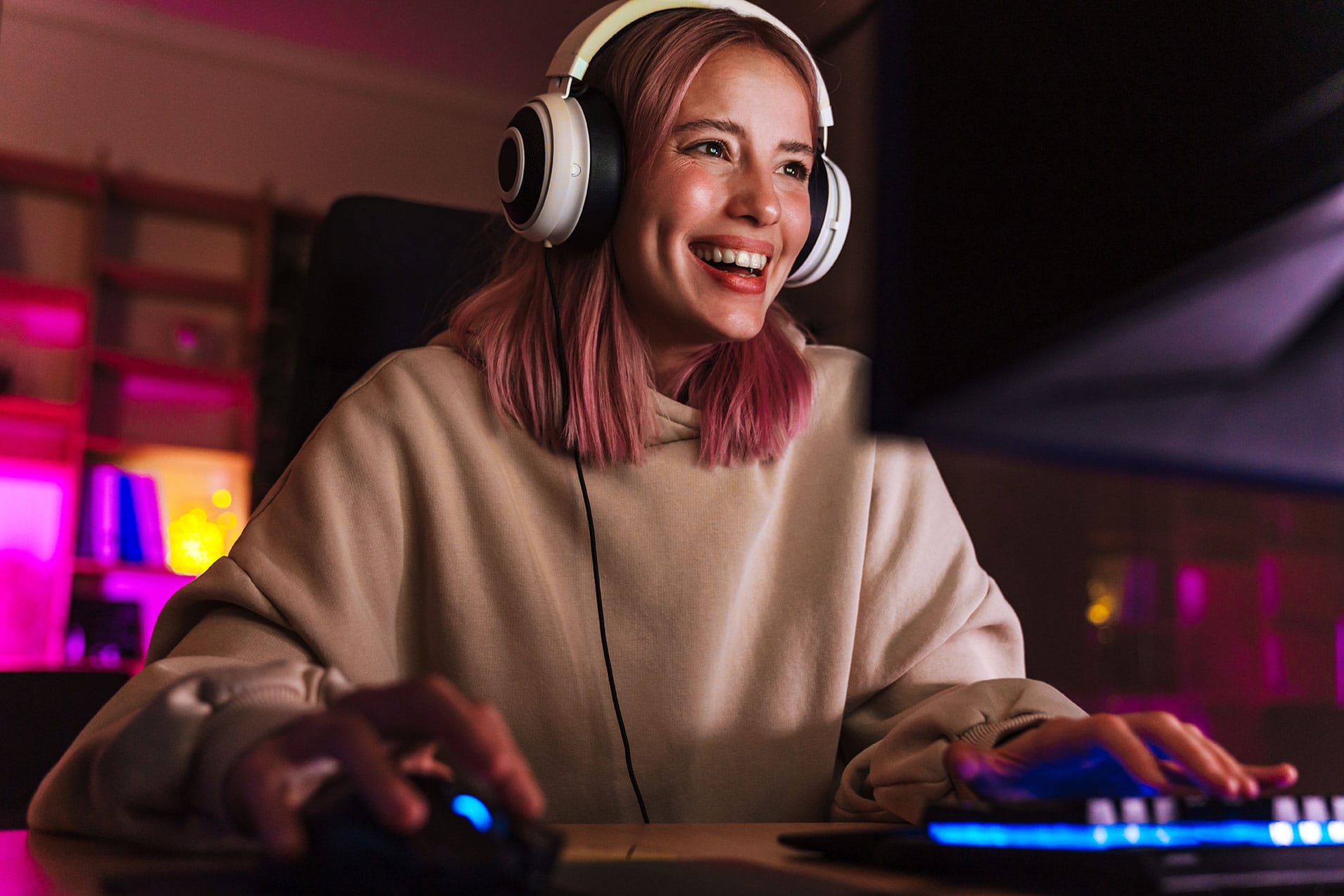 Gamer smiling while wearing headphones in a colorful gaming setup