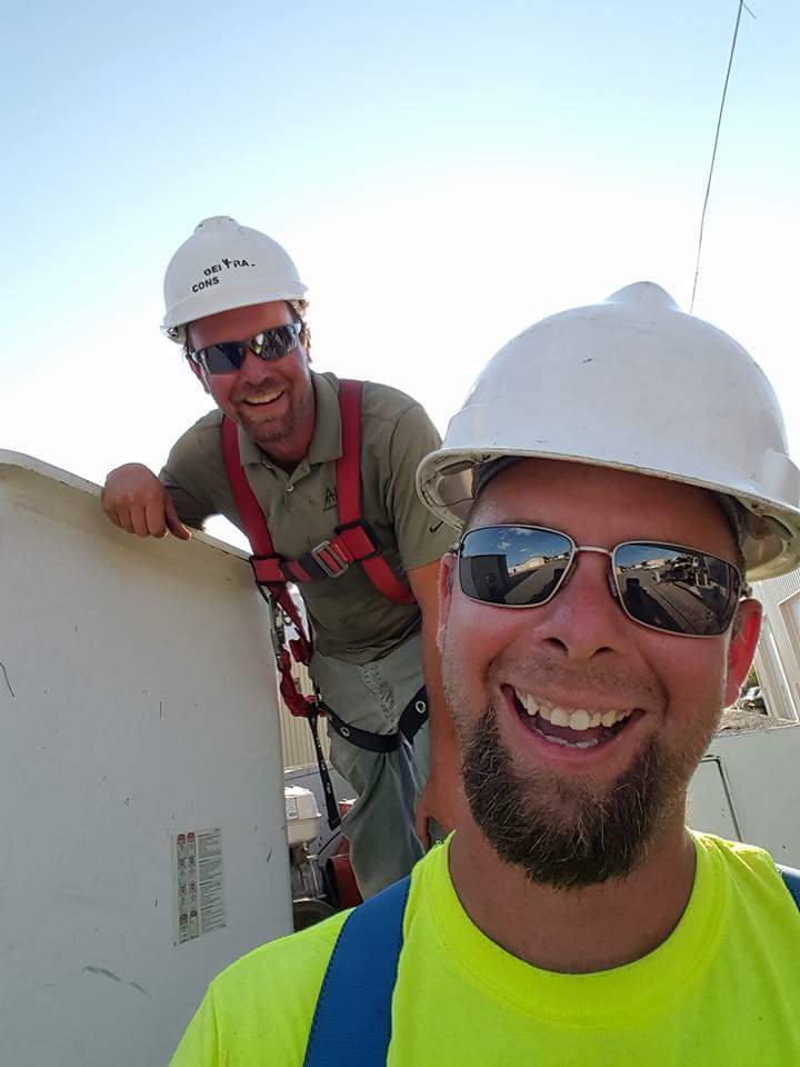 Two men smiling and wearing a harness