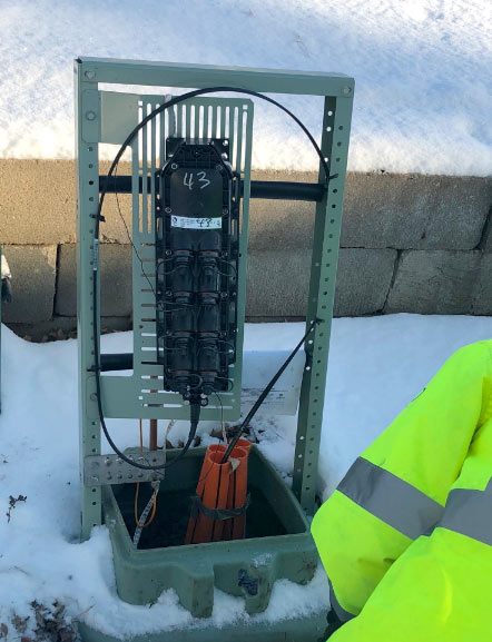 ALLO Fiber technician hooking a temporary fiber drop to a backyard pedestal.